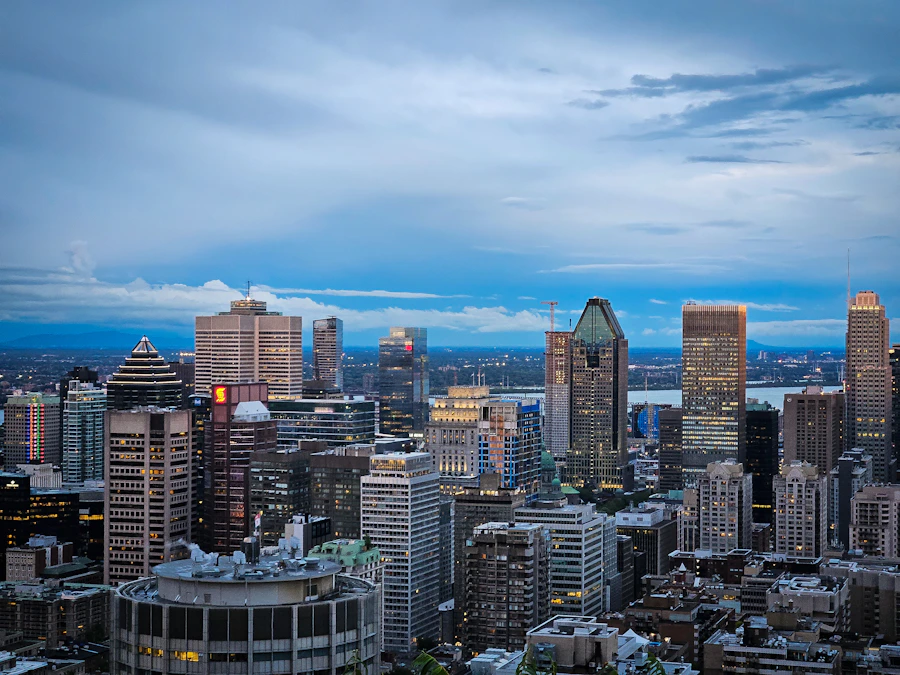 Montreal city viewed at night from an elevated point, with the downtown skyline illuminated and the St. Lawrence River visible in the background
