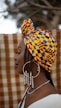 A woman wearing a yellow and blue head wrap