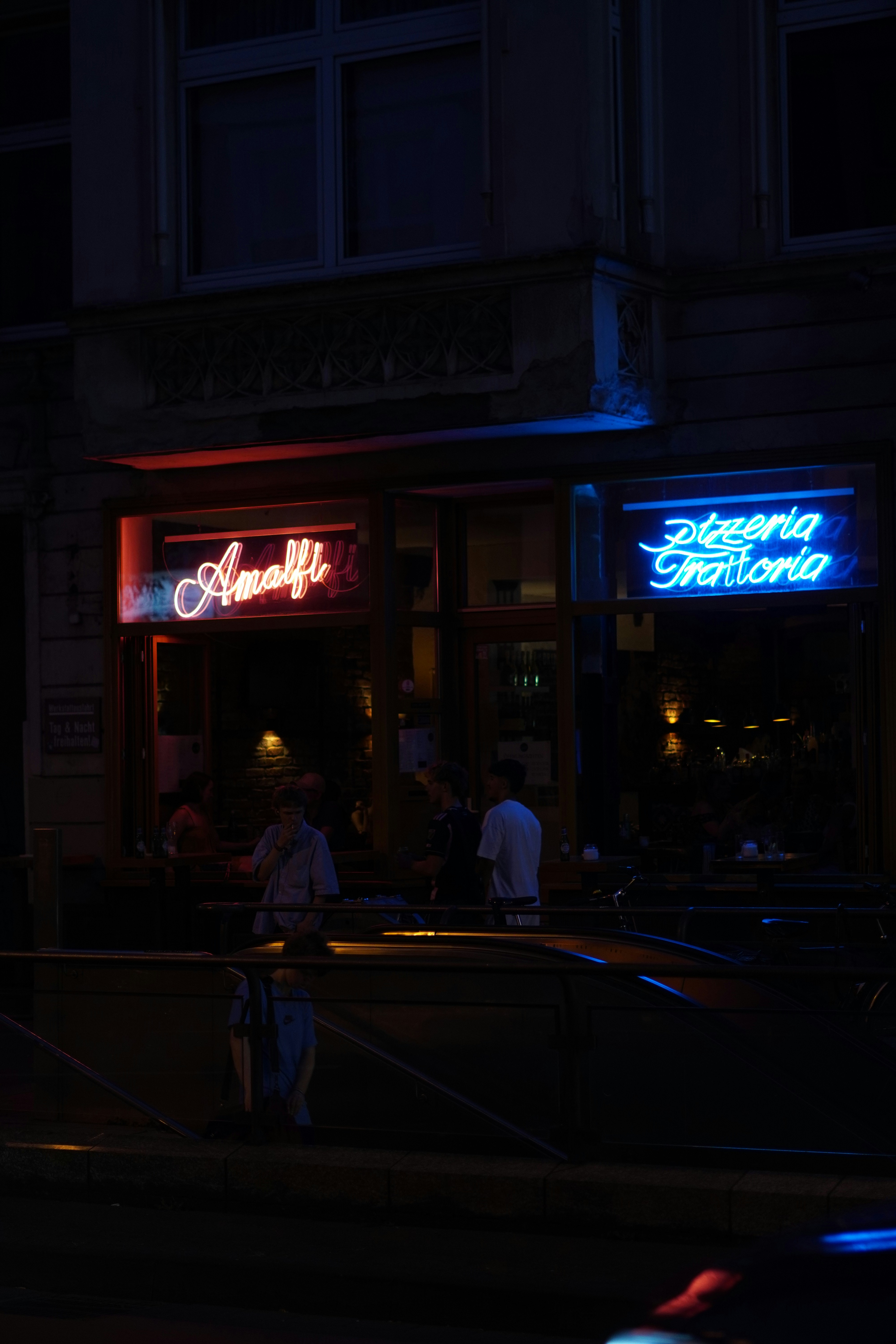 A dark city street at night with a neon sign