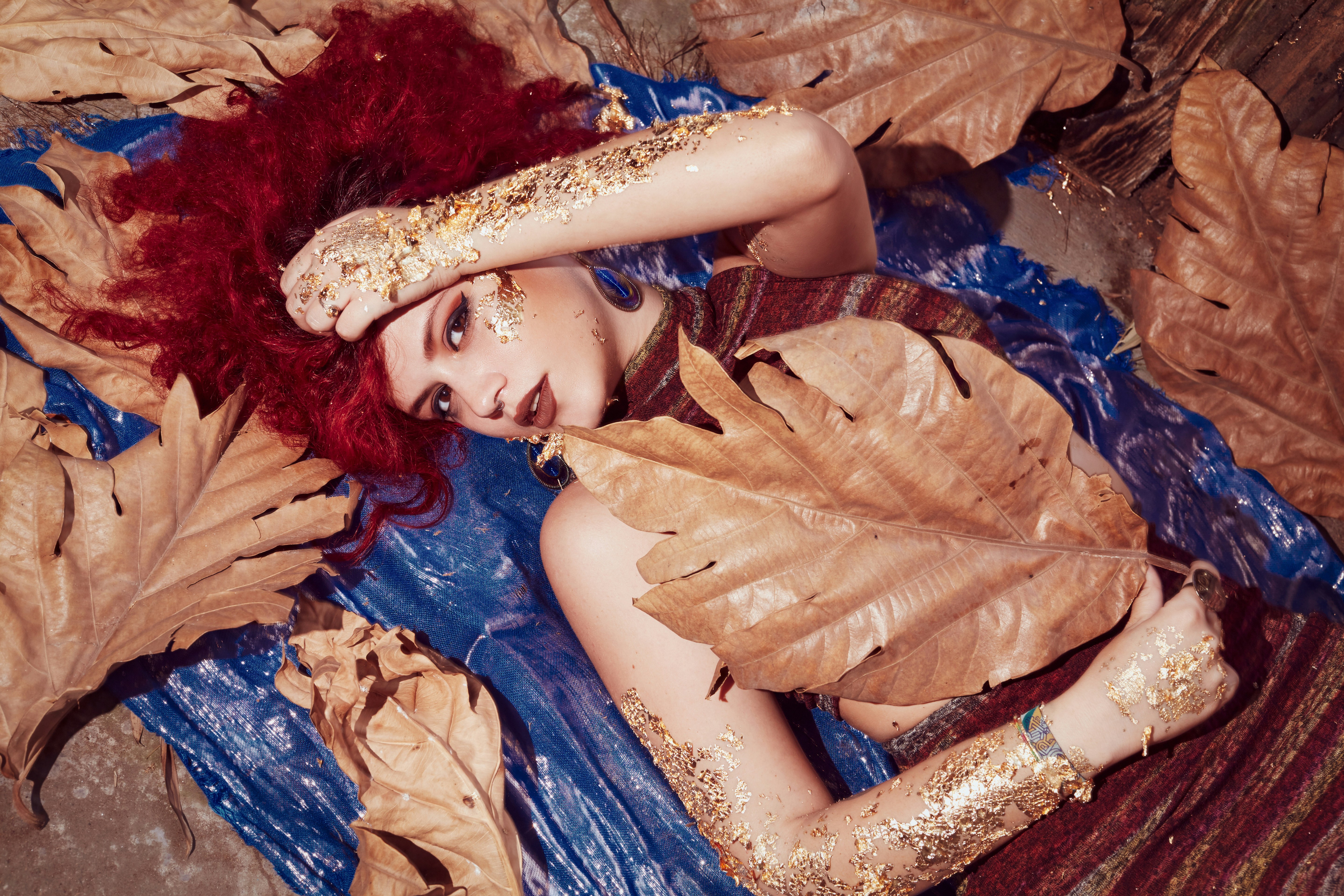 A woman laying on a bed covered in leaves