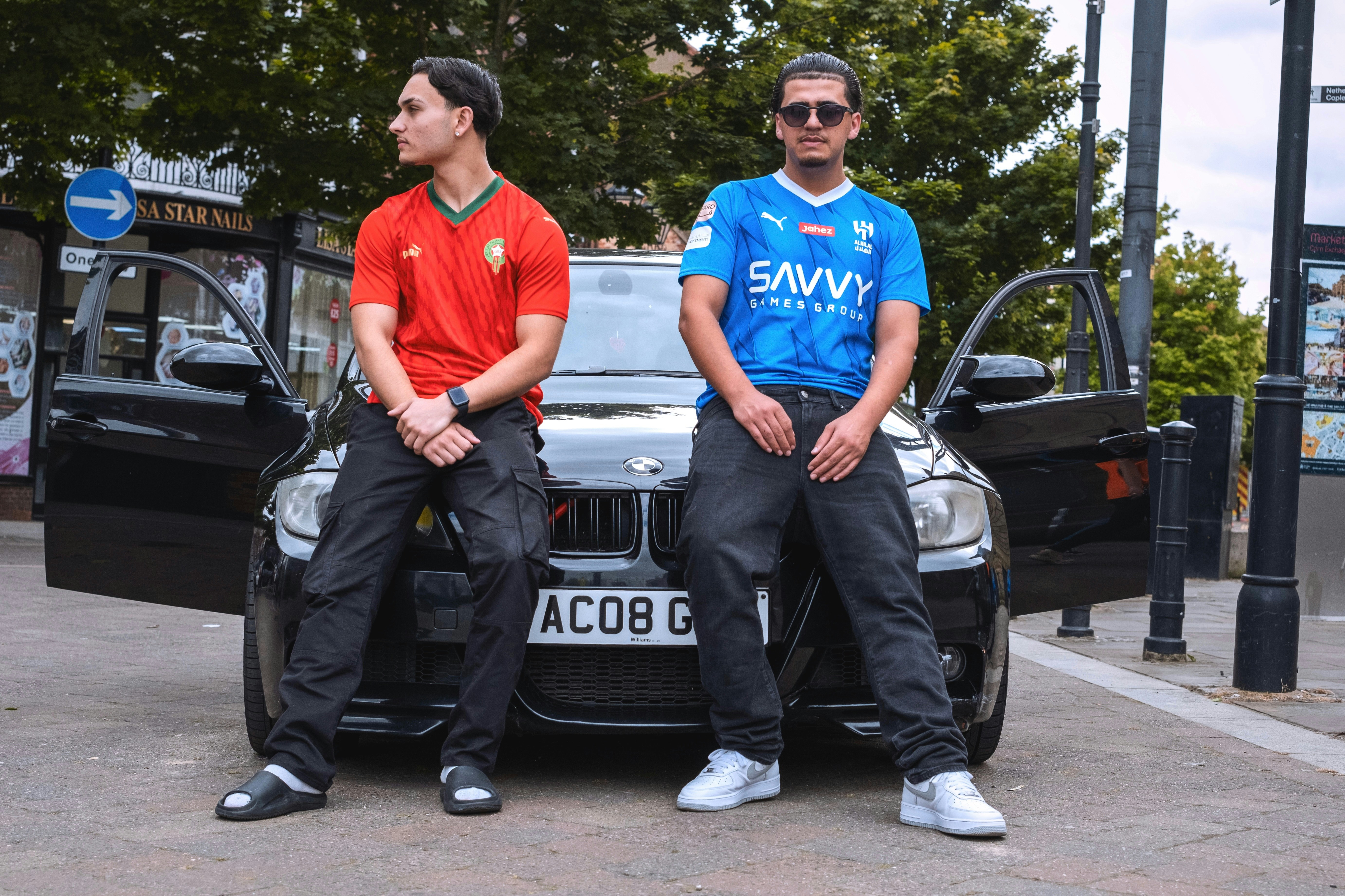 Two men sitting on the hood of a car