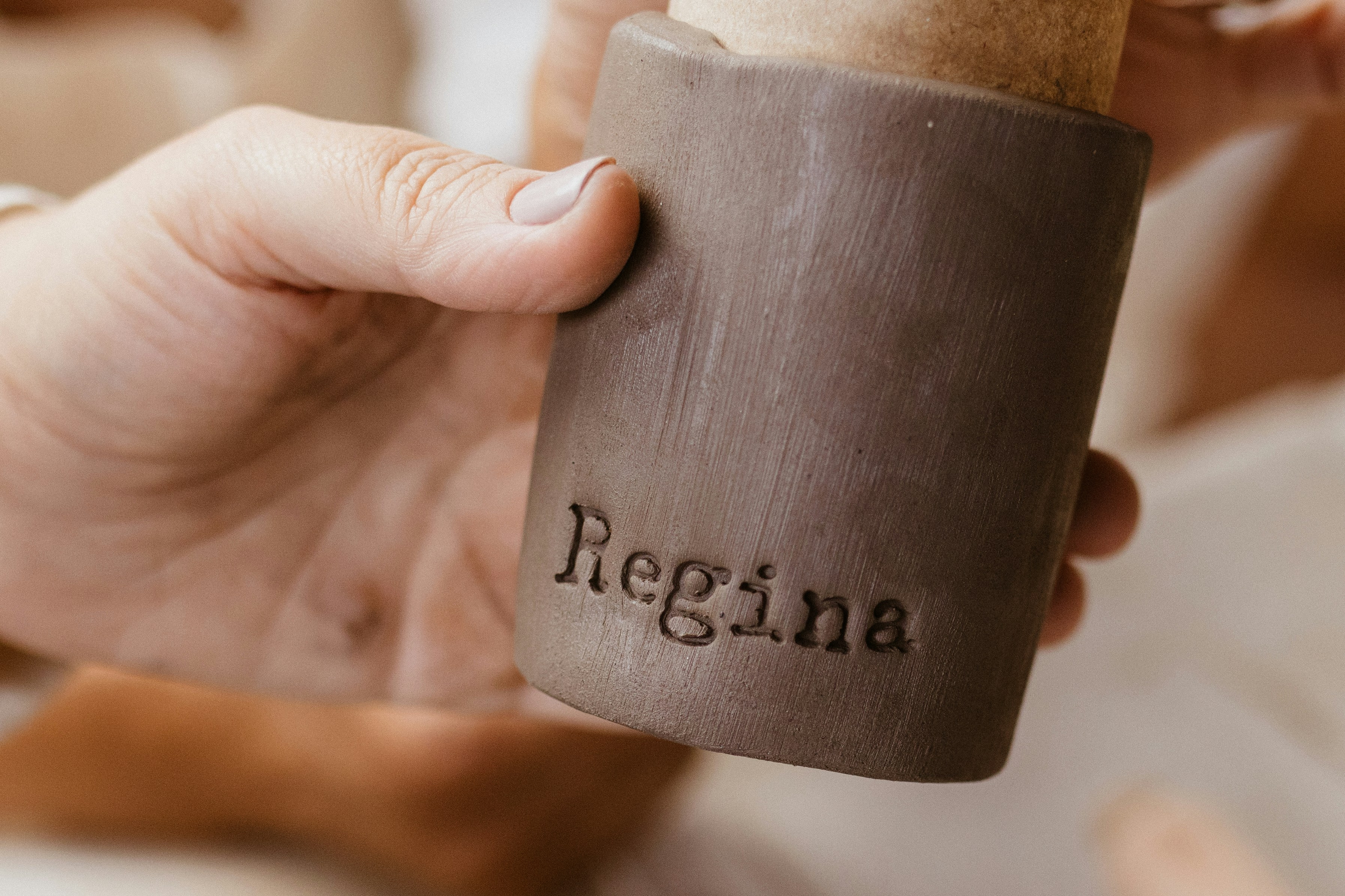 A person holding a coffee cup with the word negina written on it