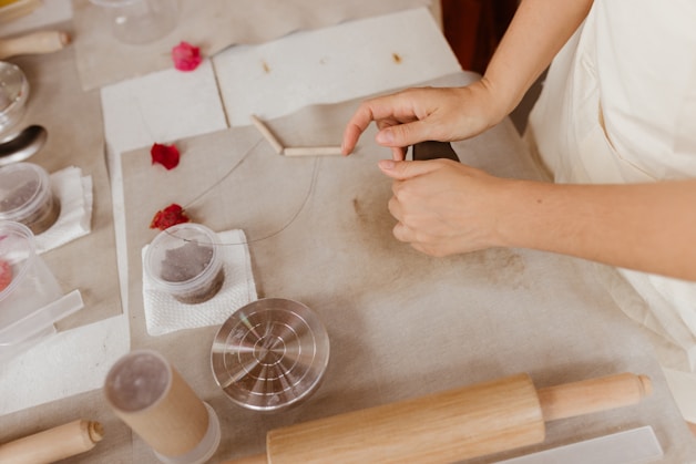 A woman in a white dress is making something