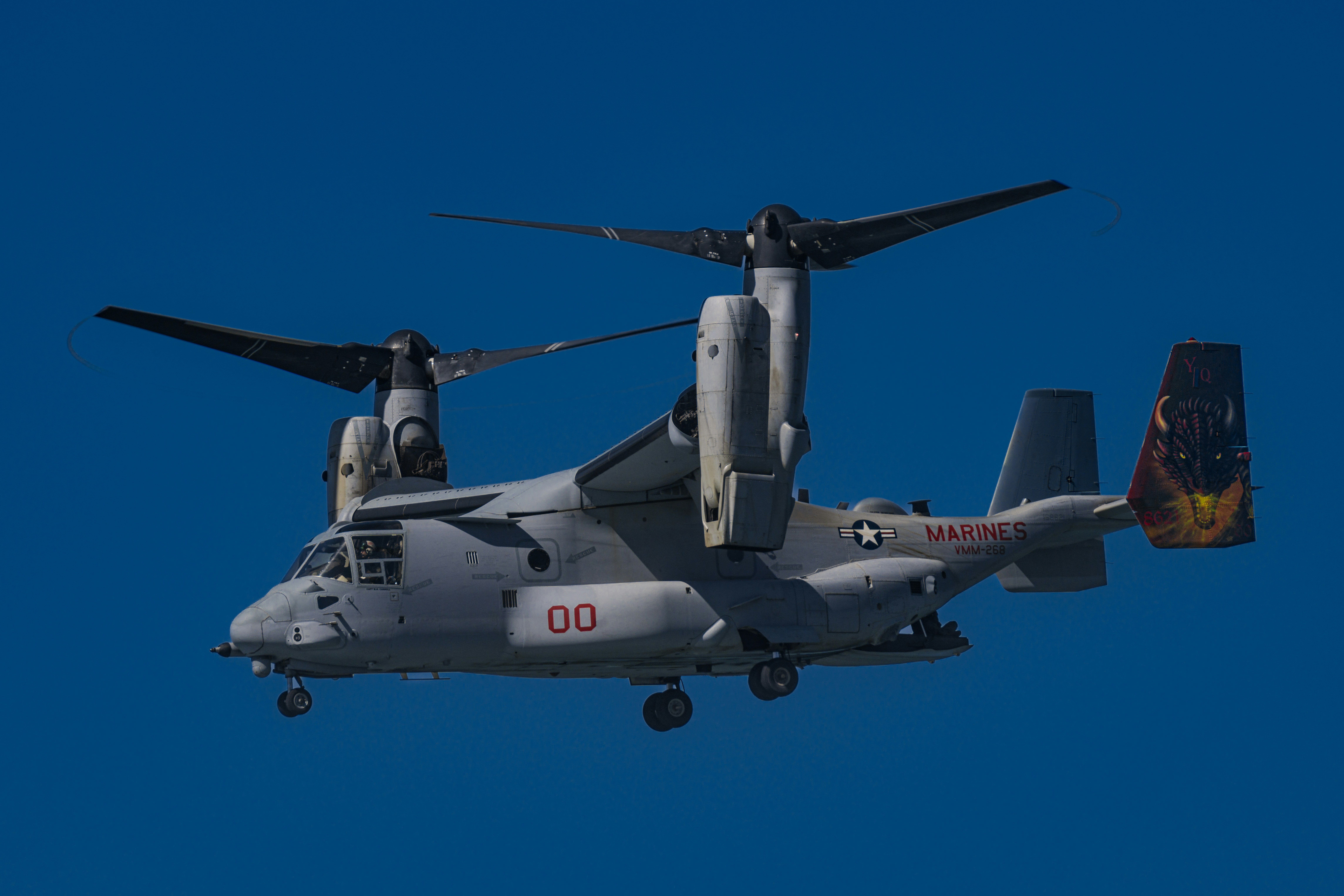 A large military helicopter flying through a blue sky