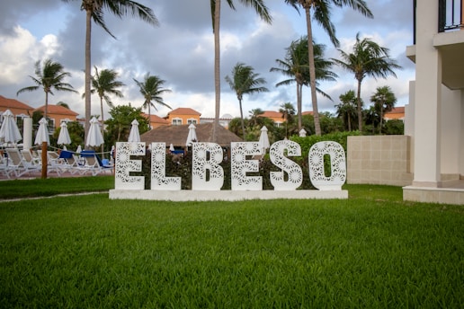 A sign that says el beso in front of some palm trees