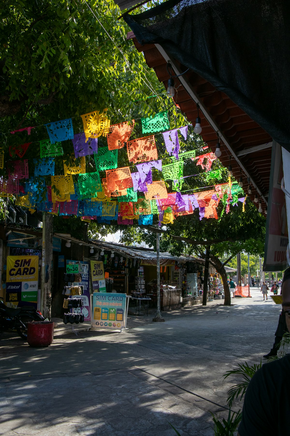 Cancun Centro — a tree-lined pedestrian street in Downtown Cancun with colourful papel picado bunting and local market stalls, the real Mexican city behind the Hotel Zone
