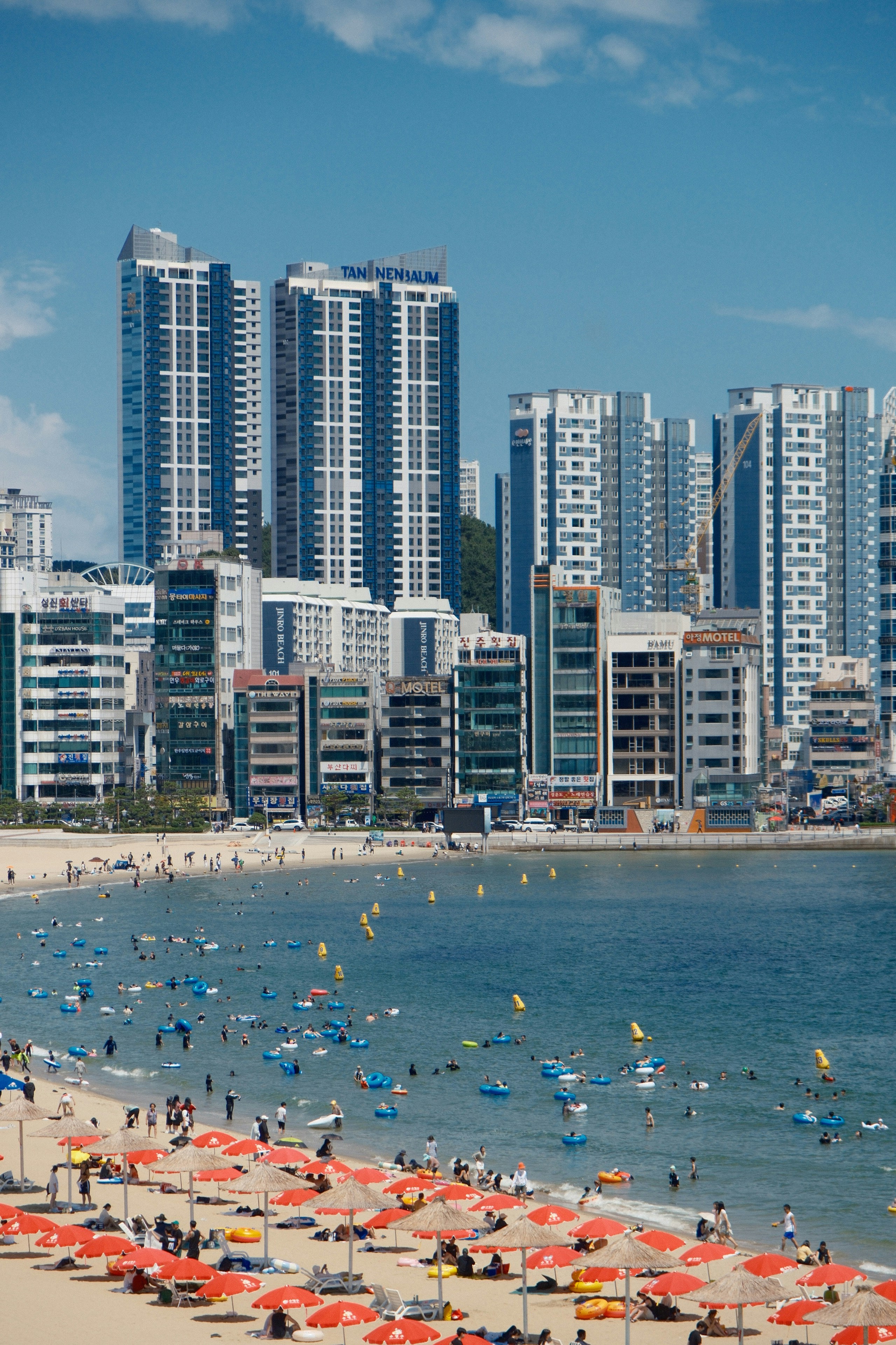 A beach filled with lots of umbrellas next to tall buildings