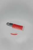 A red object with a black handle on a white surface