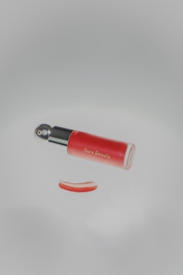 A red object with a black handle on a white surface