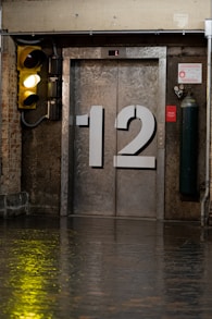 A yellow traffic light sitting next to a metal door