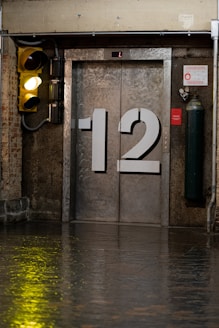 A yellow traffic light sitting next to a metal door