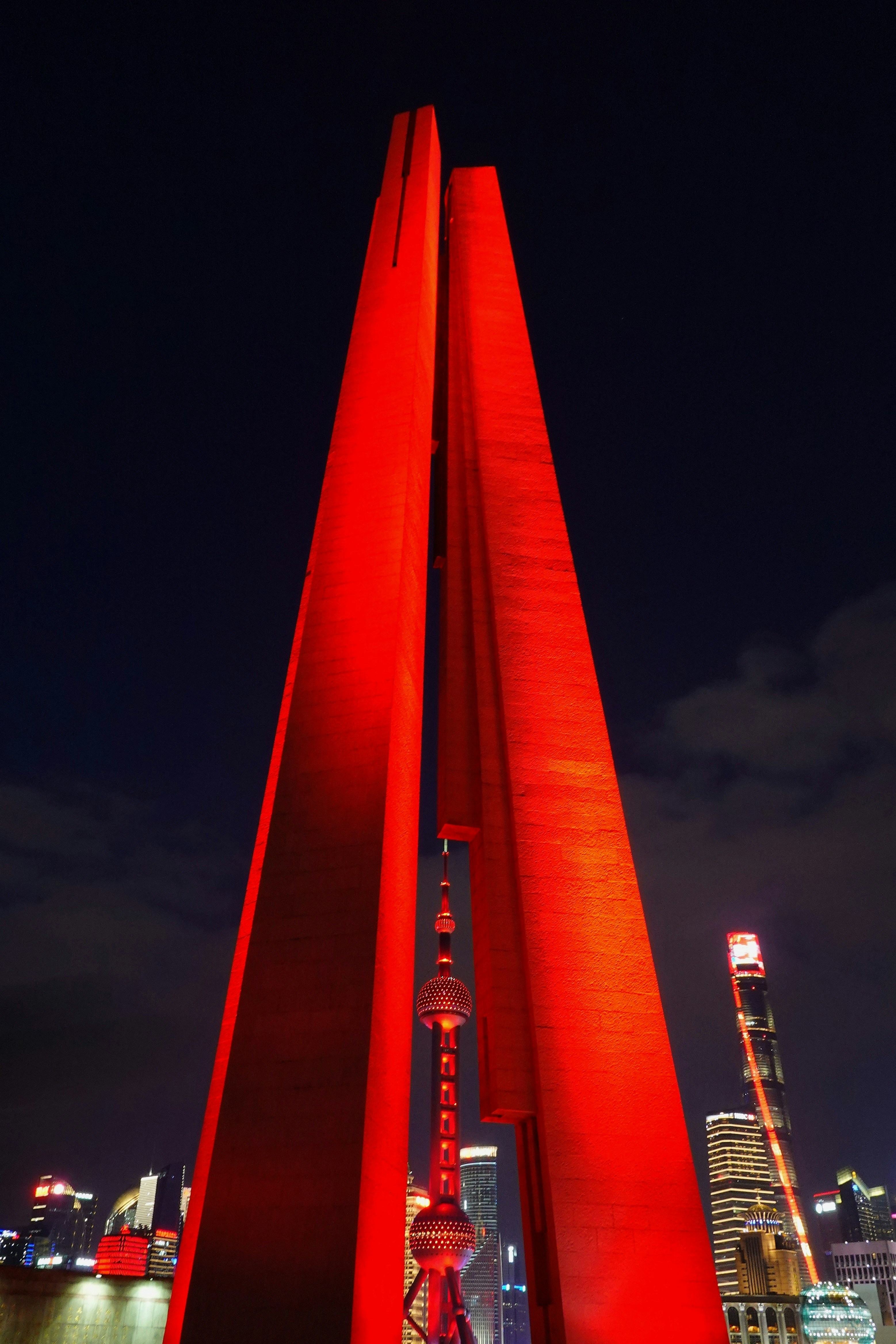 A tall red sculpture in front of a city skyline