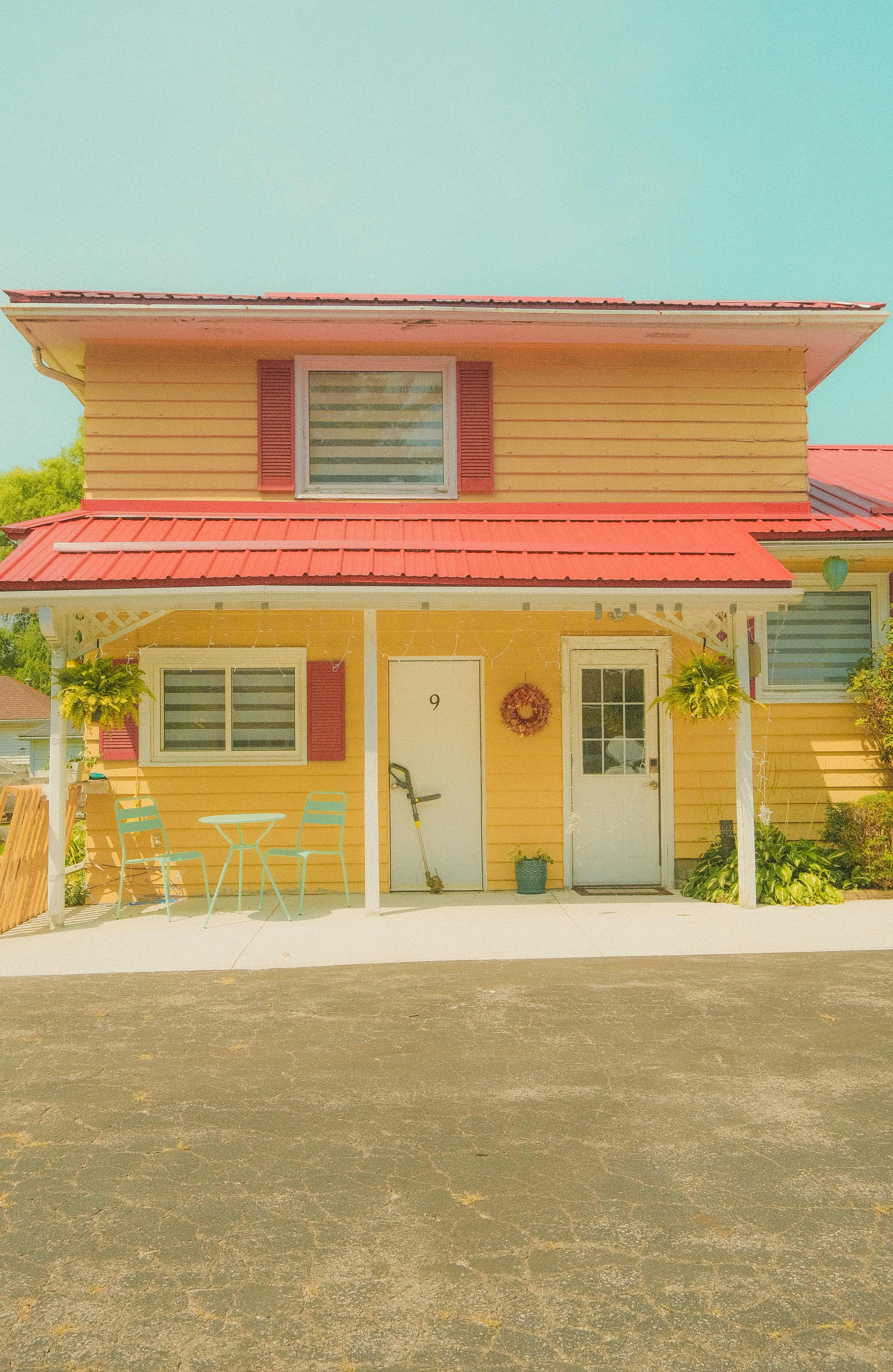 A yellow house with a red roof and a white door