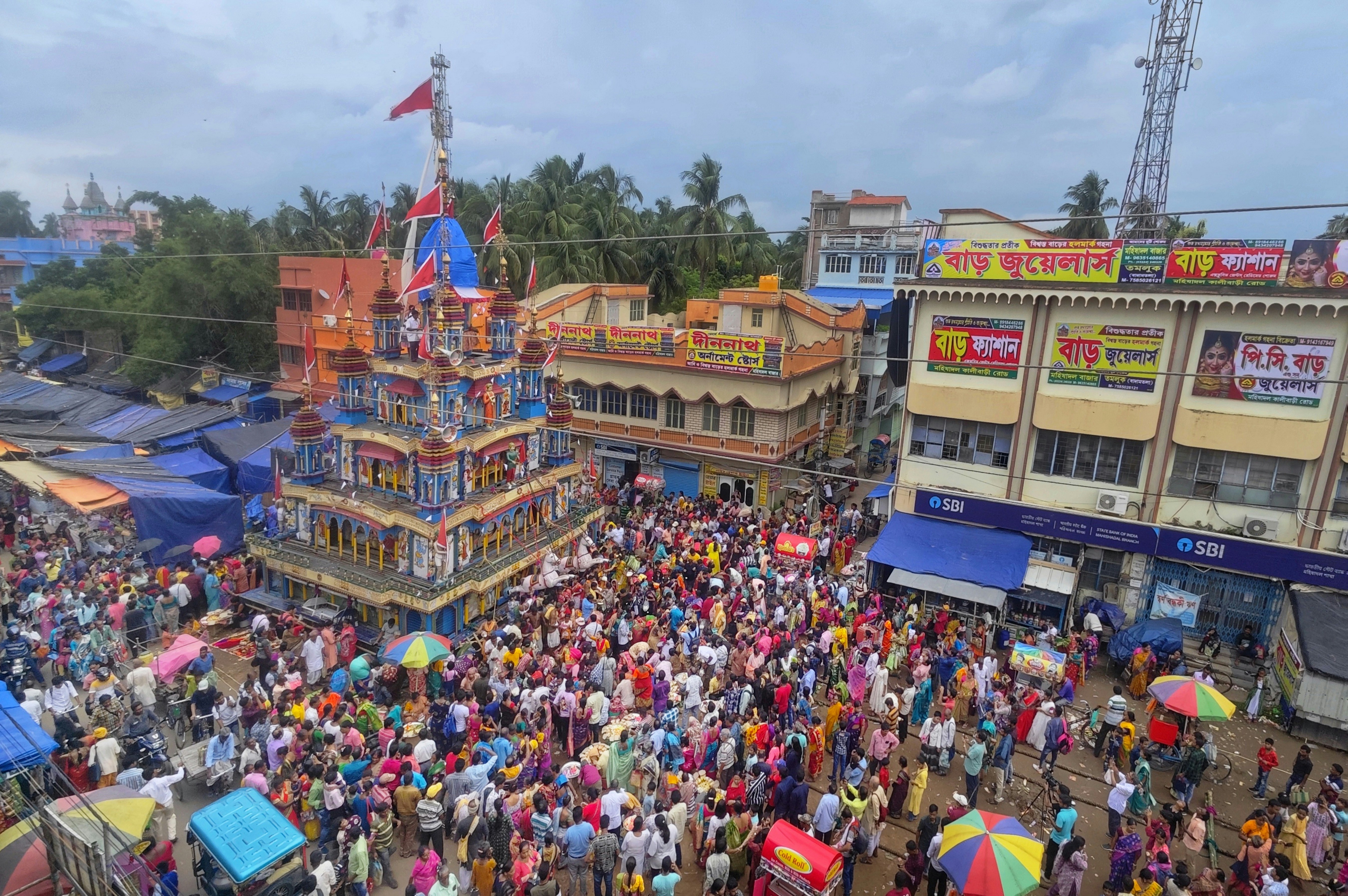 PM Modi addressing a large, enthusiastic rally in West Bengal, with numerous party flags waving in the background.