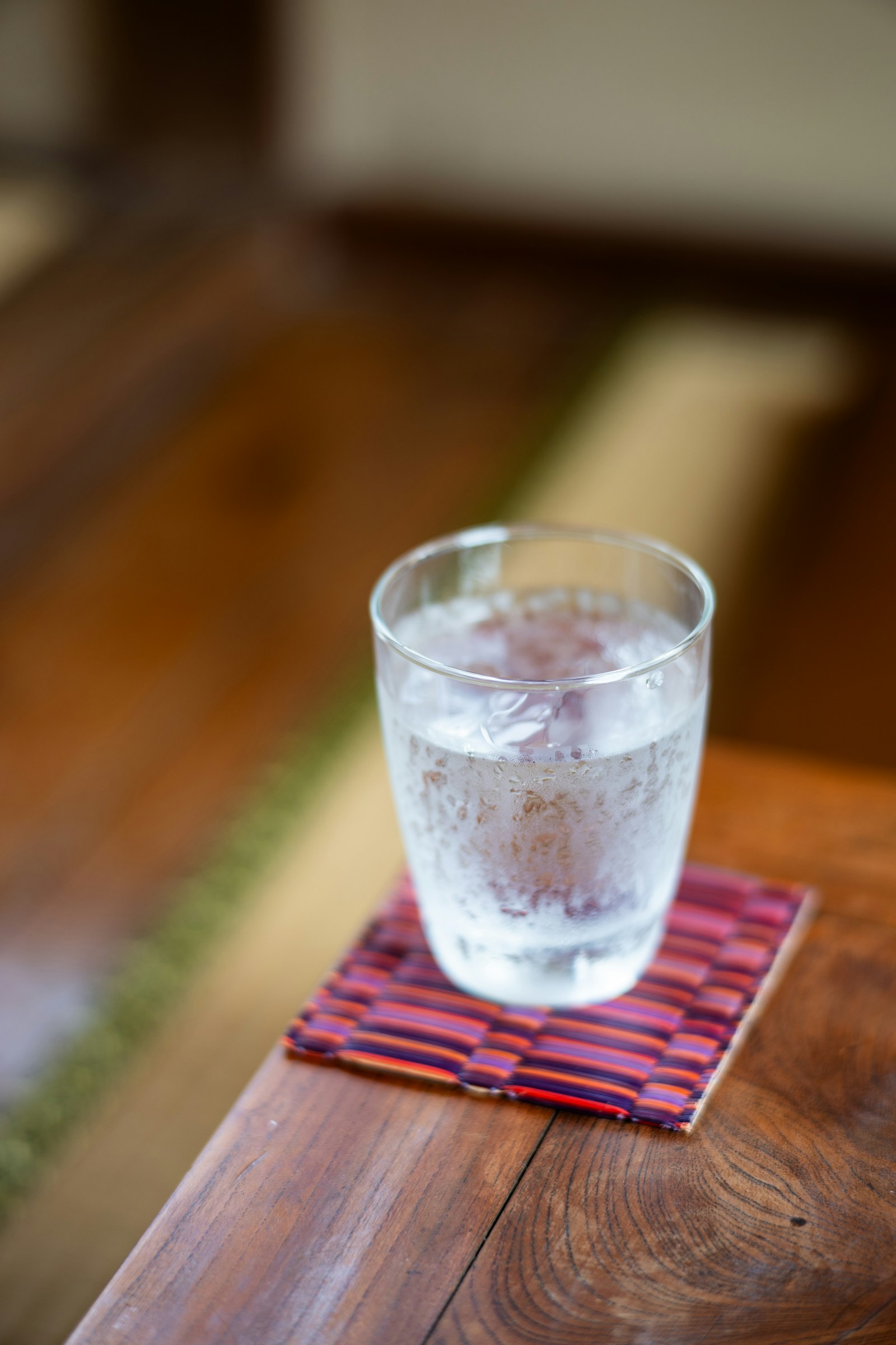 A cold glass of water on a coaster on a wooden table