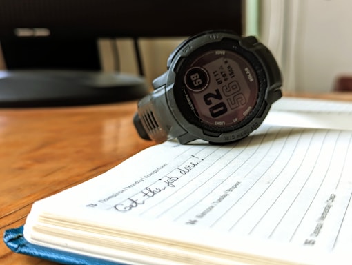 A watch sitting on top of a notebook on a table