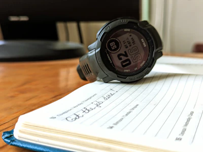 A watch sitting on top of a notebook on a table