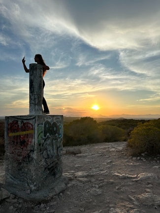 A woman standing on top of a cement pillar