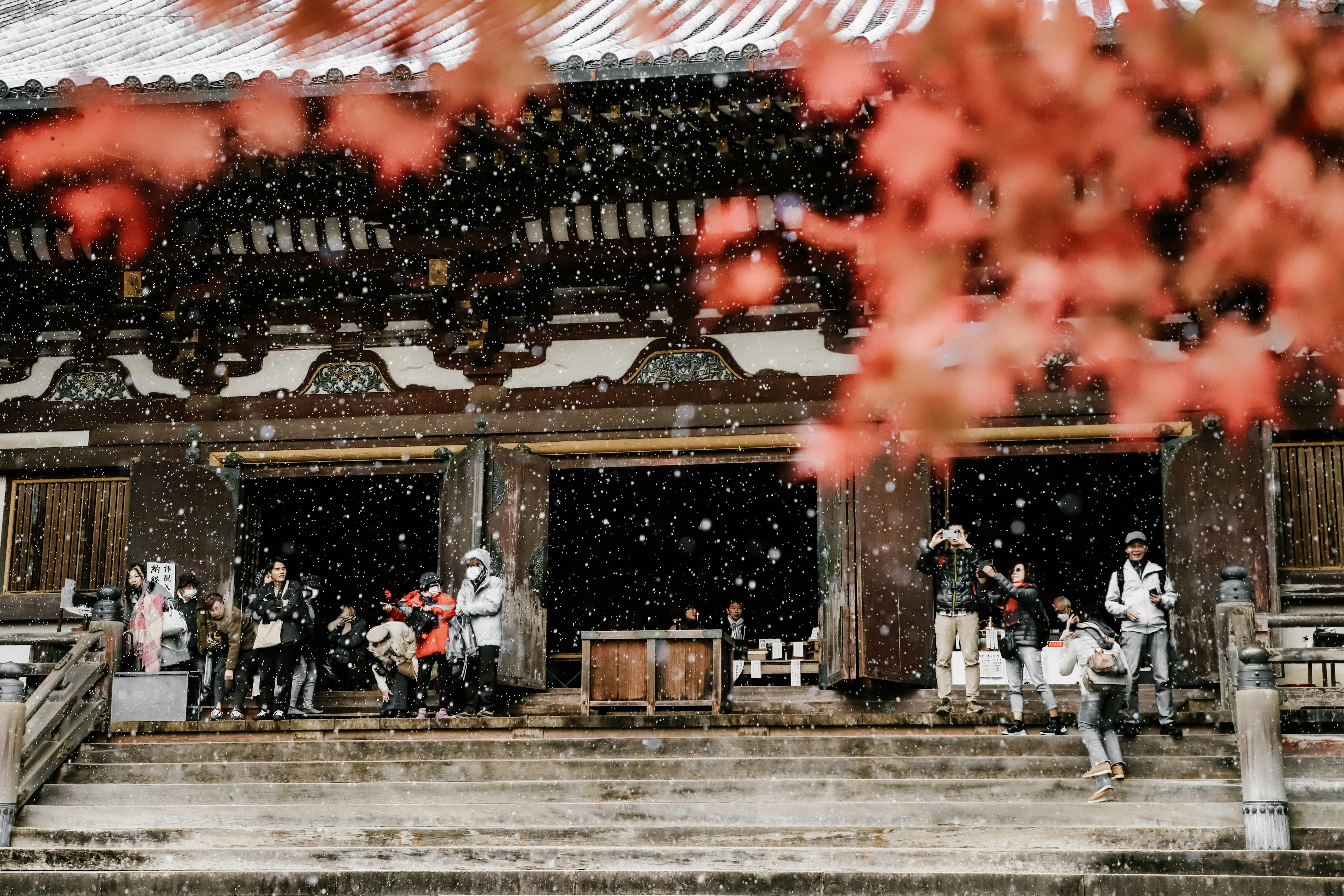 A group of people standing outside of a building in the snow, 