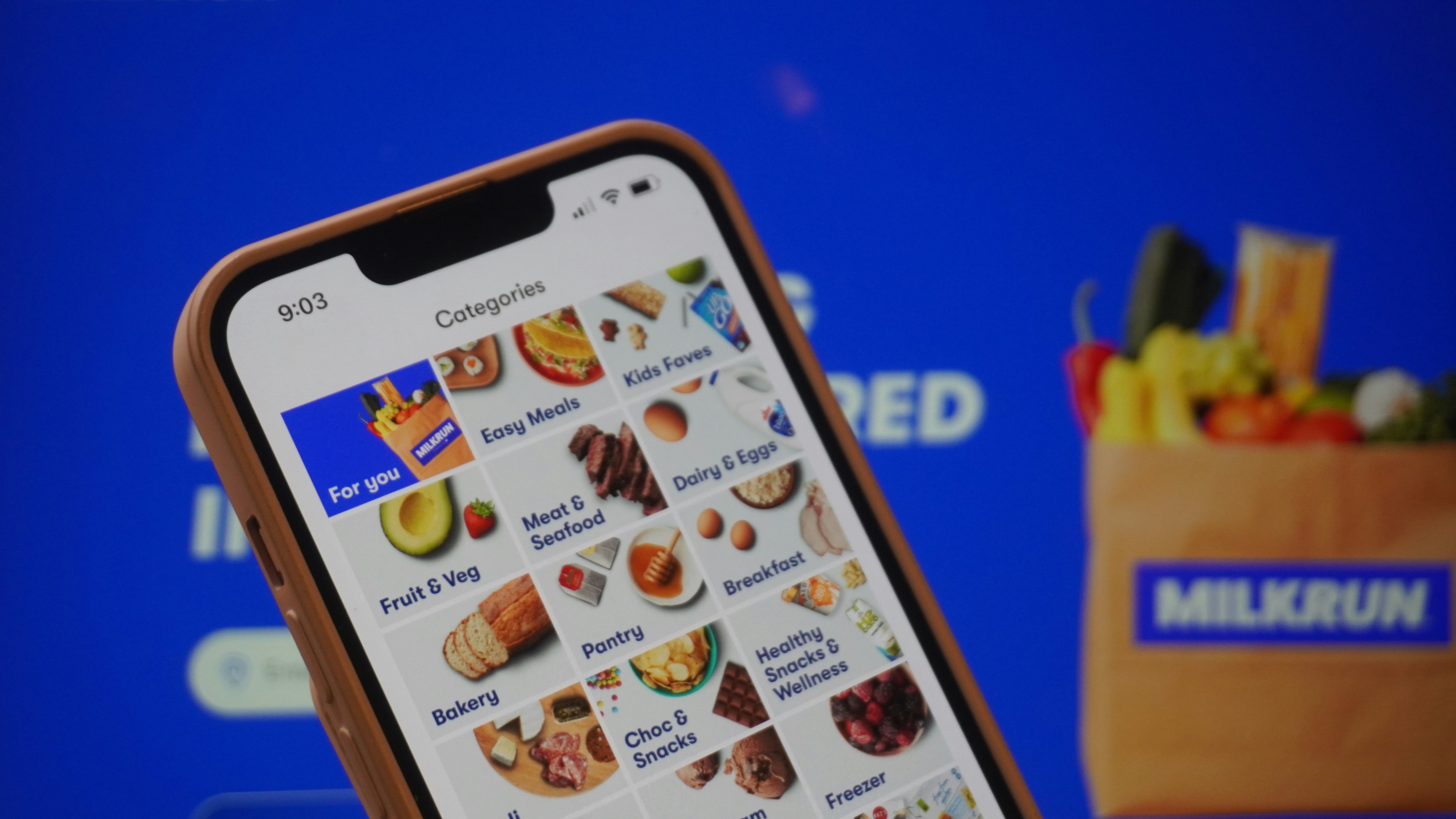 A person holding a cell phone in front of a screen