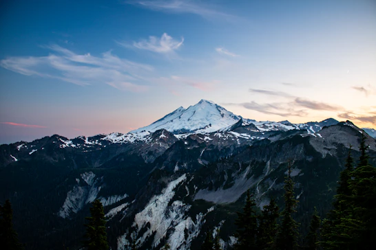 A view of a snow covered mountain at sunset