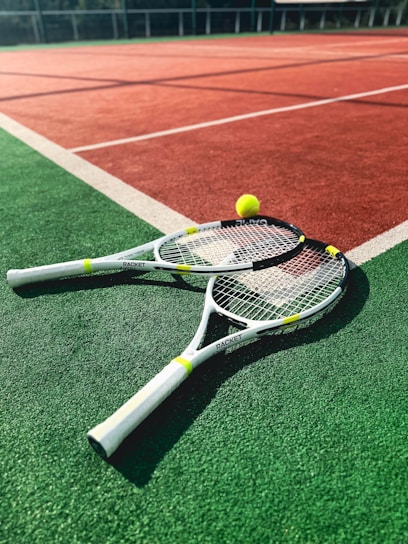 A tennis racket and two tennis balls on a tennis court
