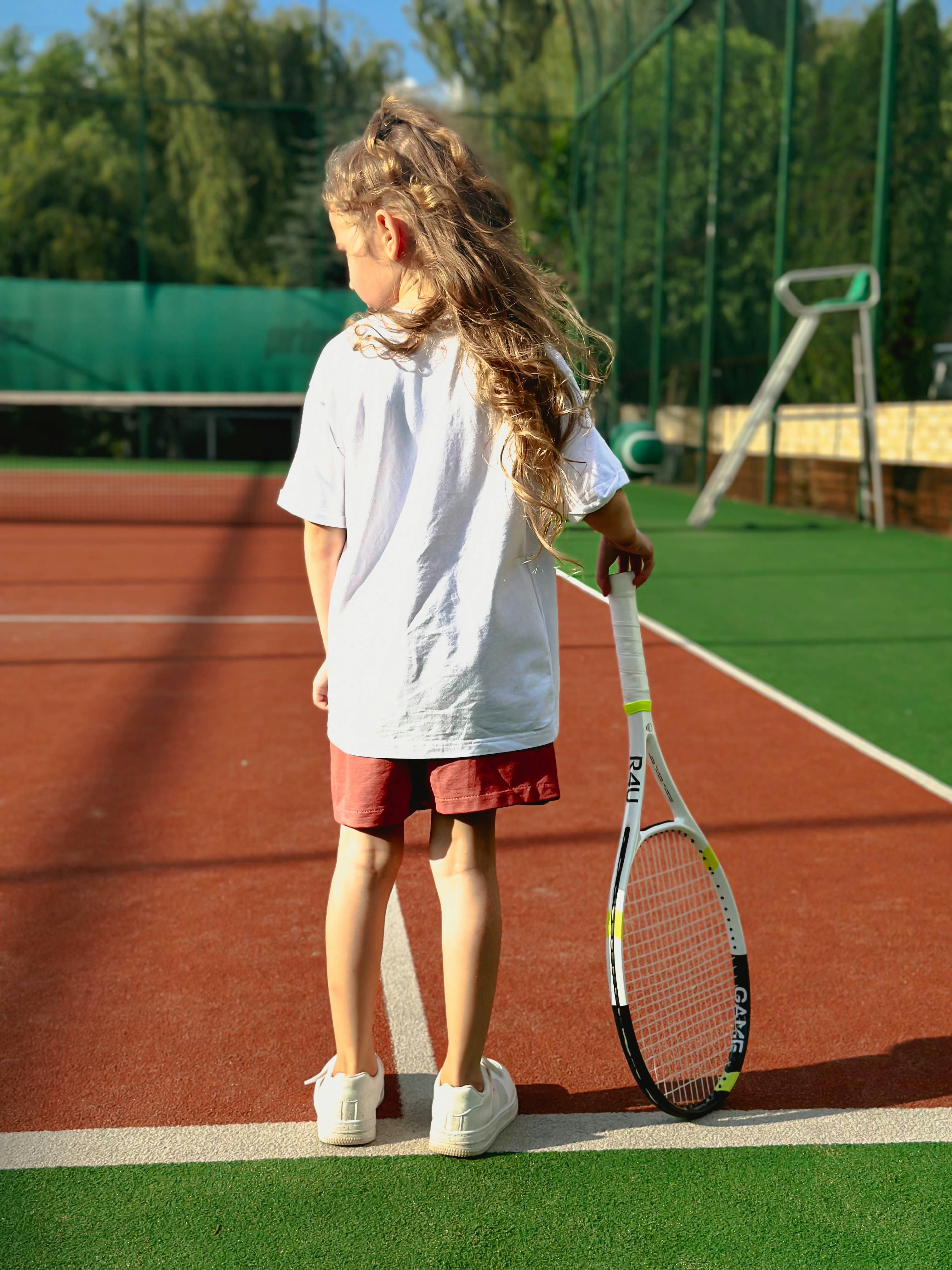 A young girl holding a tennis racquet on a tennis court
