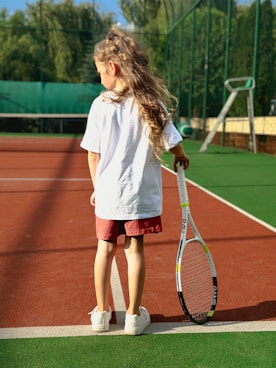 A young girl holding a tennis racquet on a tennis court