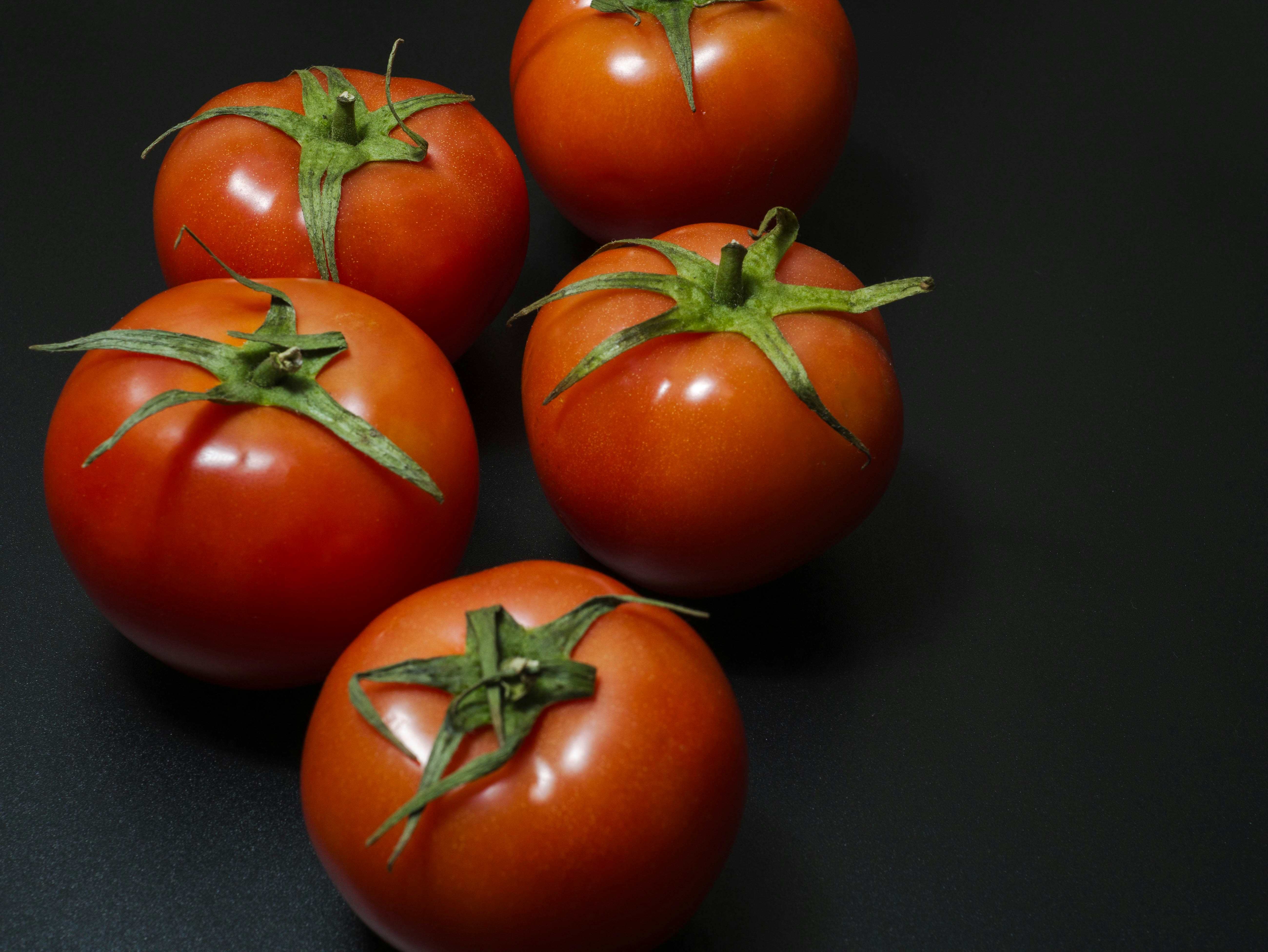 A group of five tomatoes sitting on top of a table