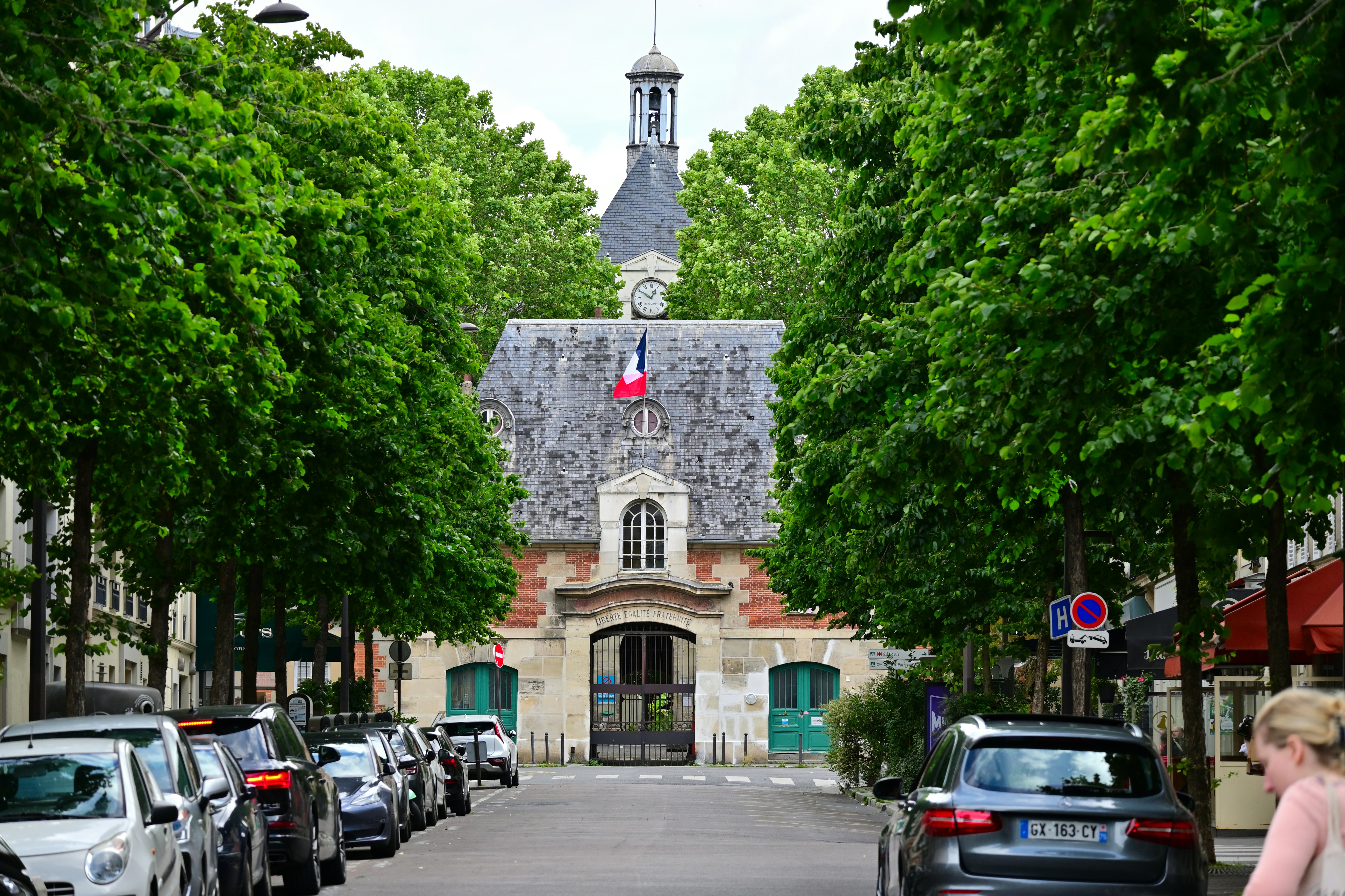 A woman walking down a street next to parked cars