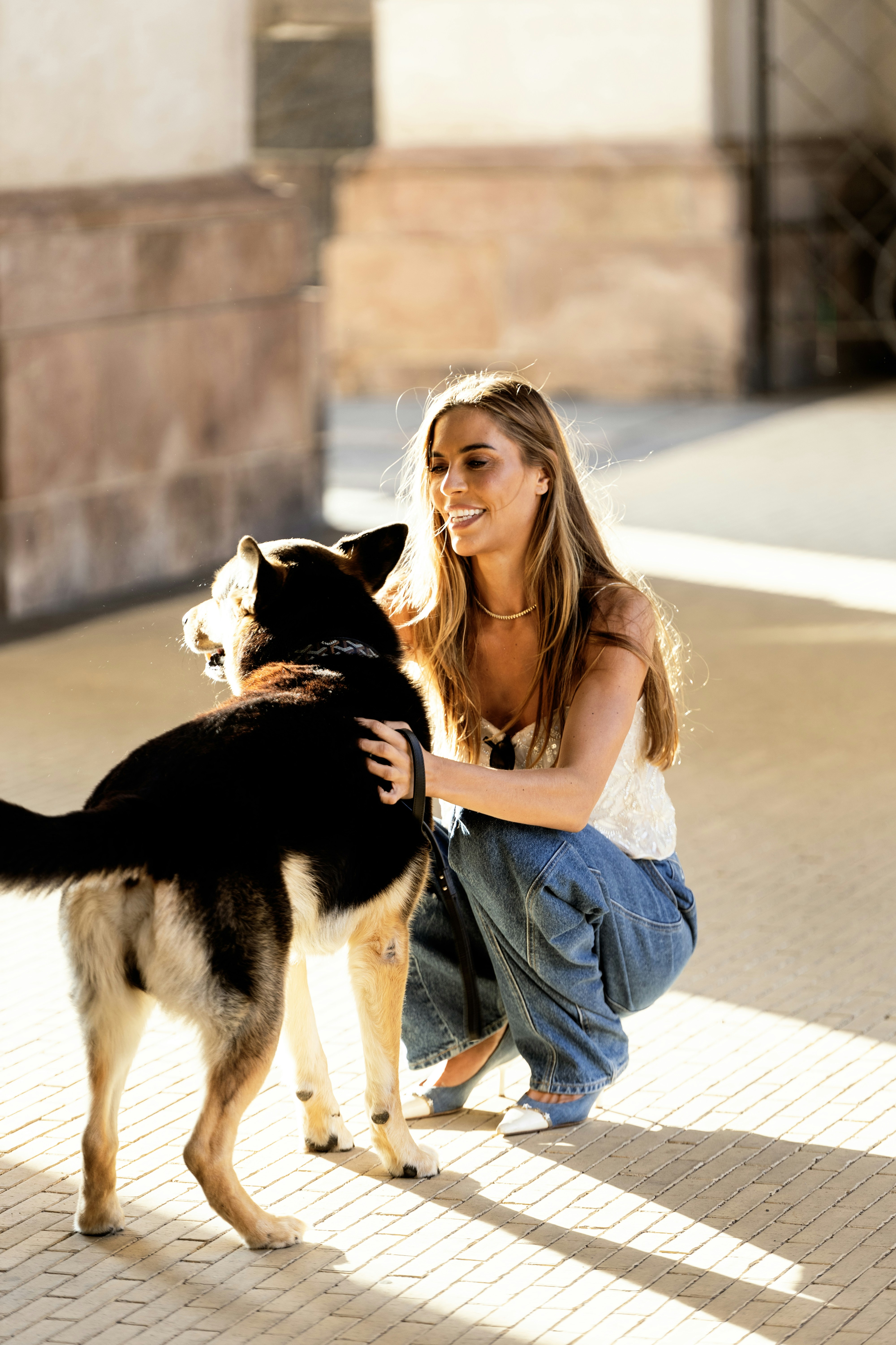 A woman kneeling down next to a black and white dog