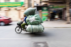 A person riding a bike with a large bag on the back of it