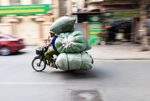 A person riding a bike with a large bag on the back of it
