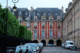 A city street lined with parked cars and tall buildings