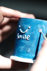 A person holding a cup with the word smile painted on it