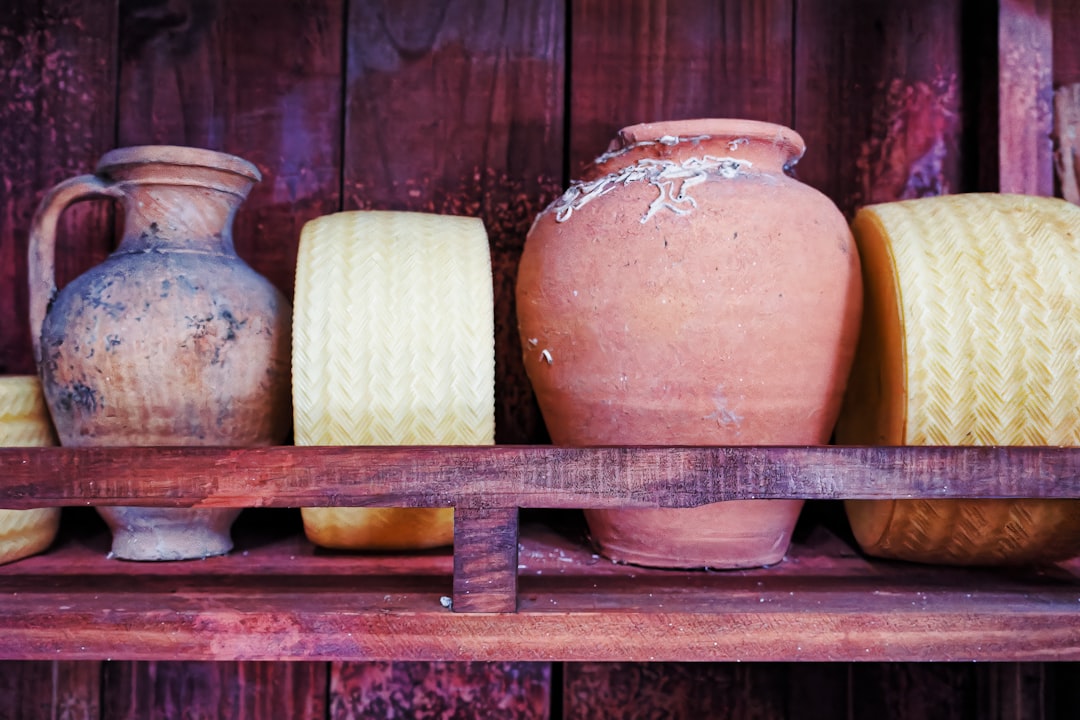 A shelf filled with vases and jars on top of a wooden shelf