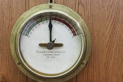 A close up of a thermometer on a wooden wall