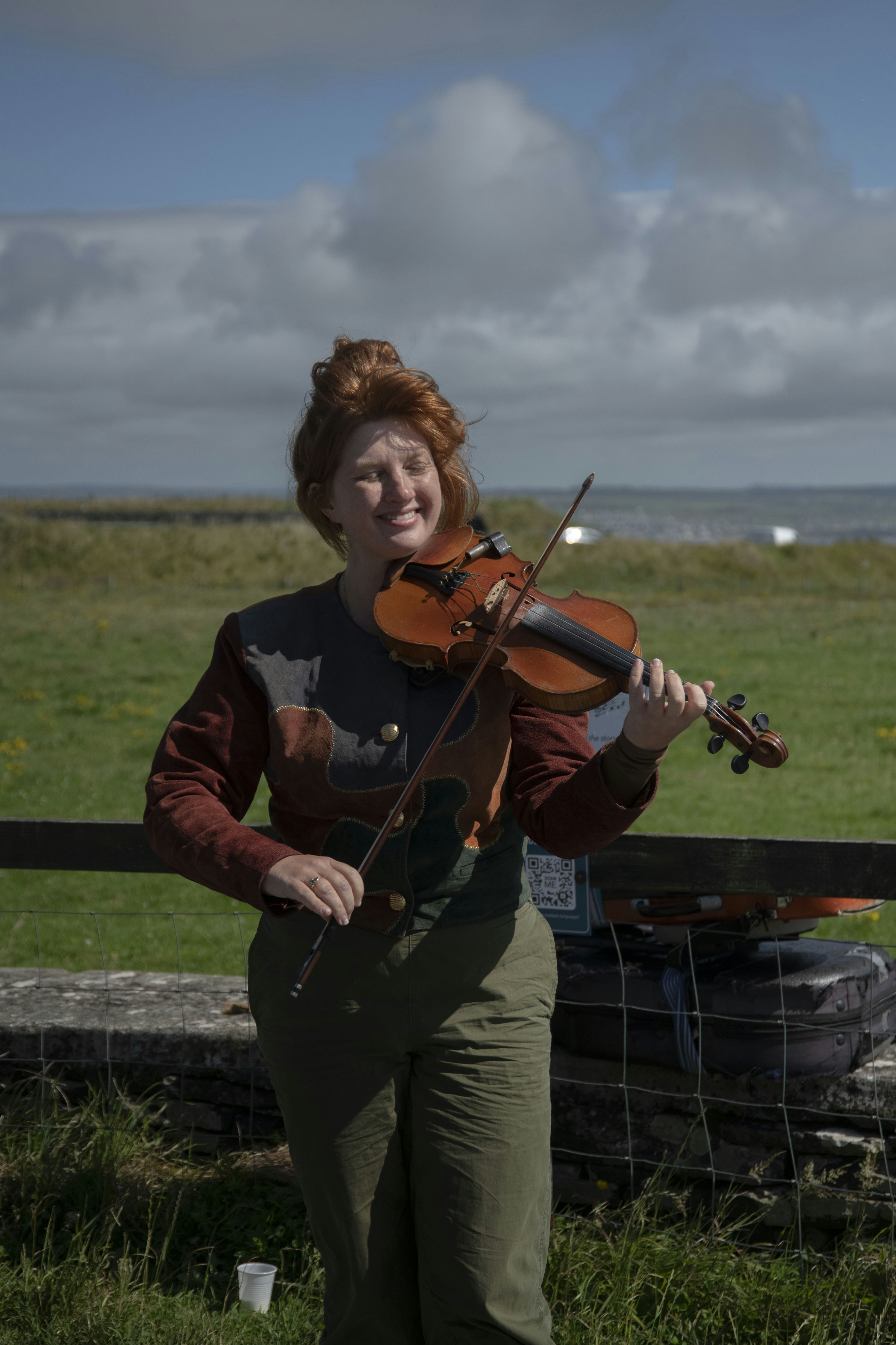 A woman with red hair playing a violin