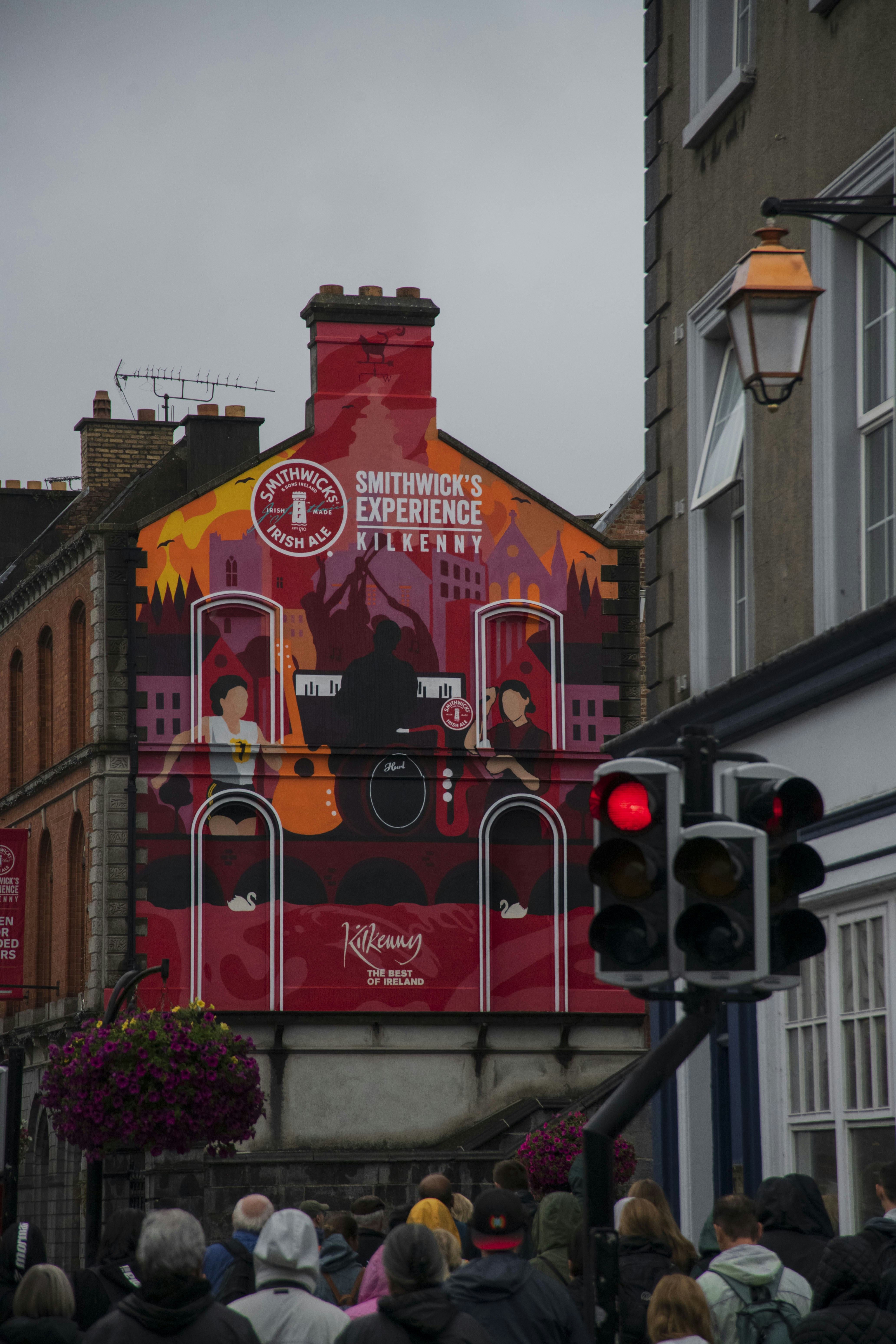 A crowd of people walking down a street next to tall buildings
