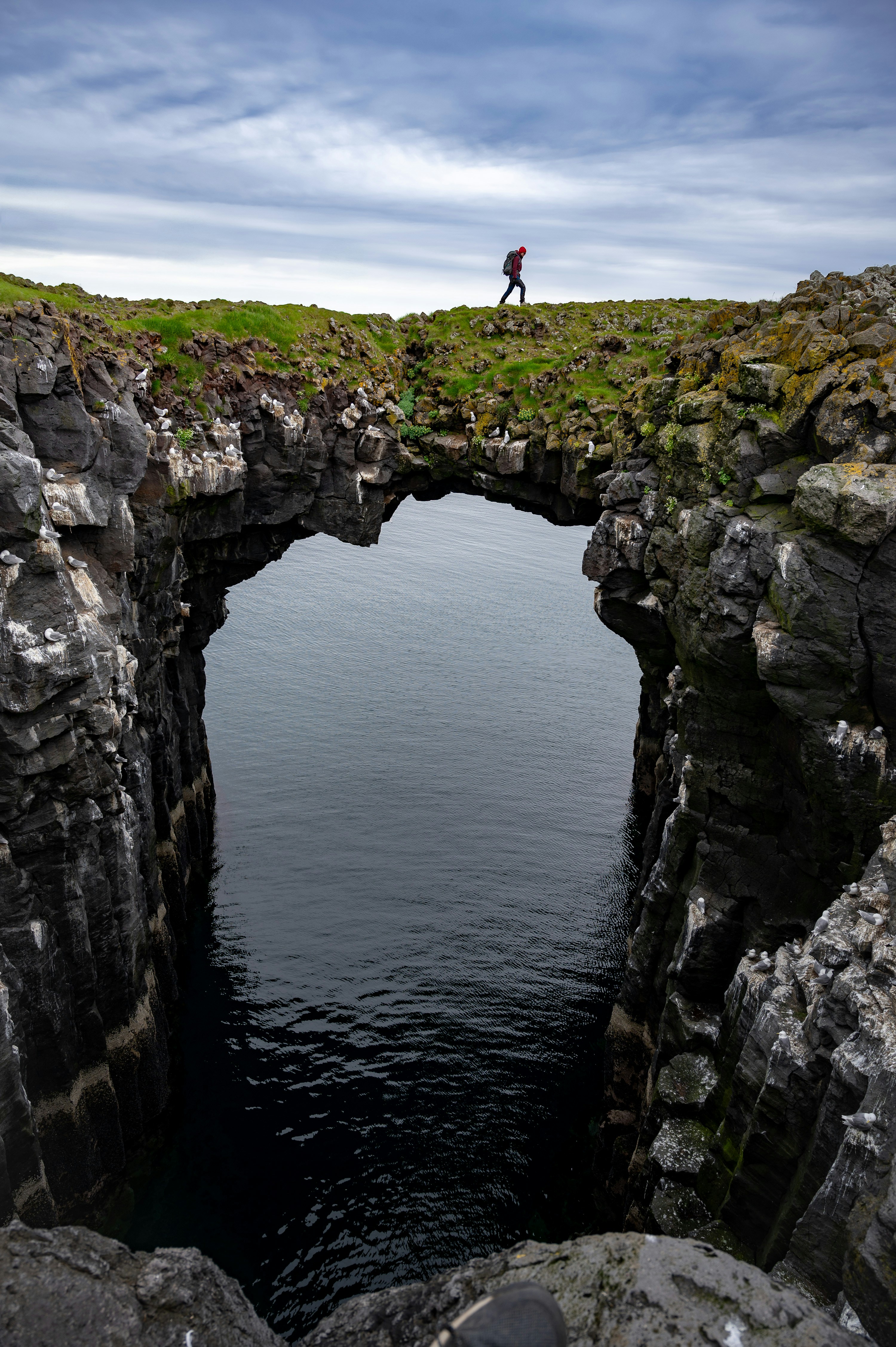 A man standing on the edge of a cliff over a body of water