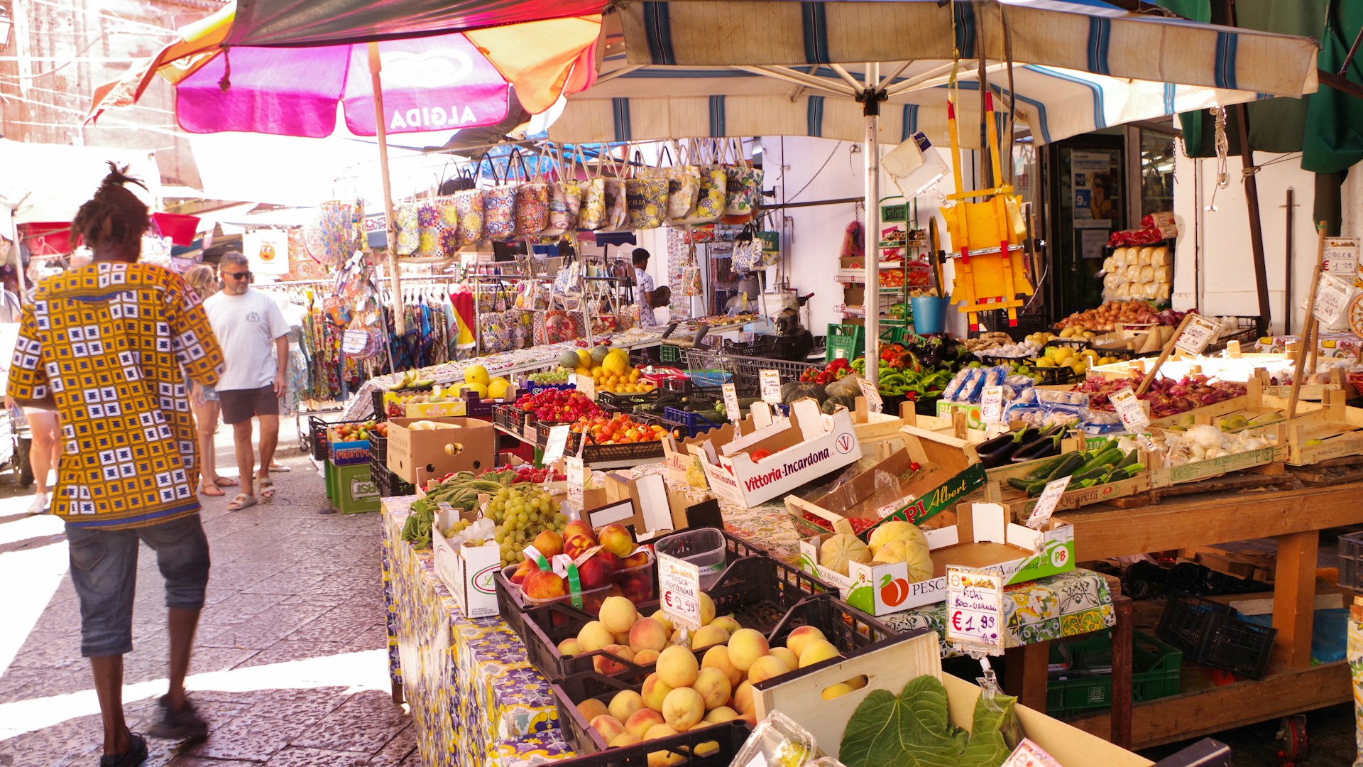 A woman standing in front of a fruit and vegetable stand