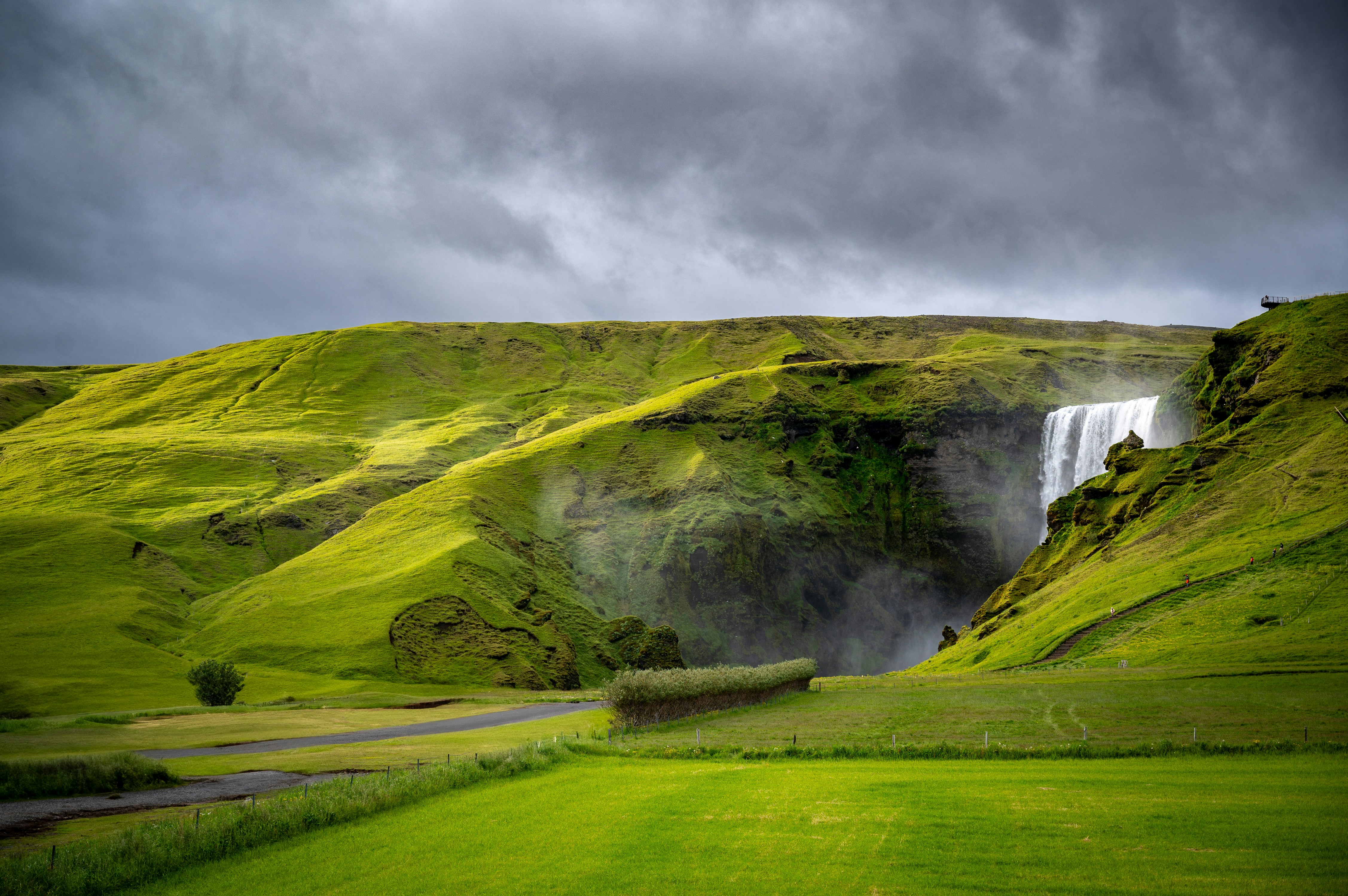 A green field with a waterfall in the background