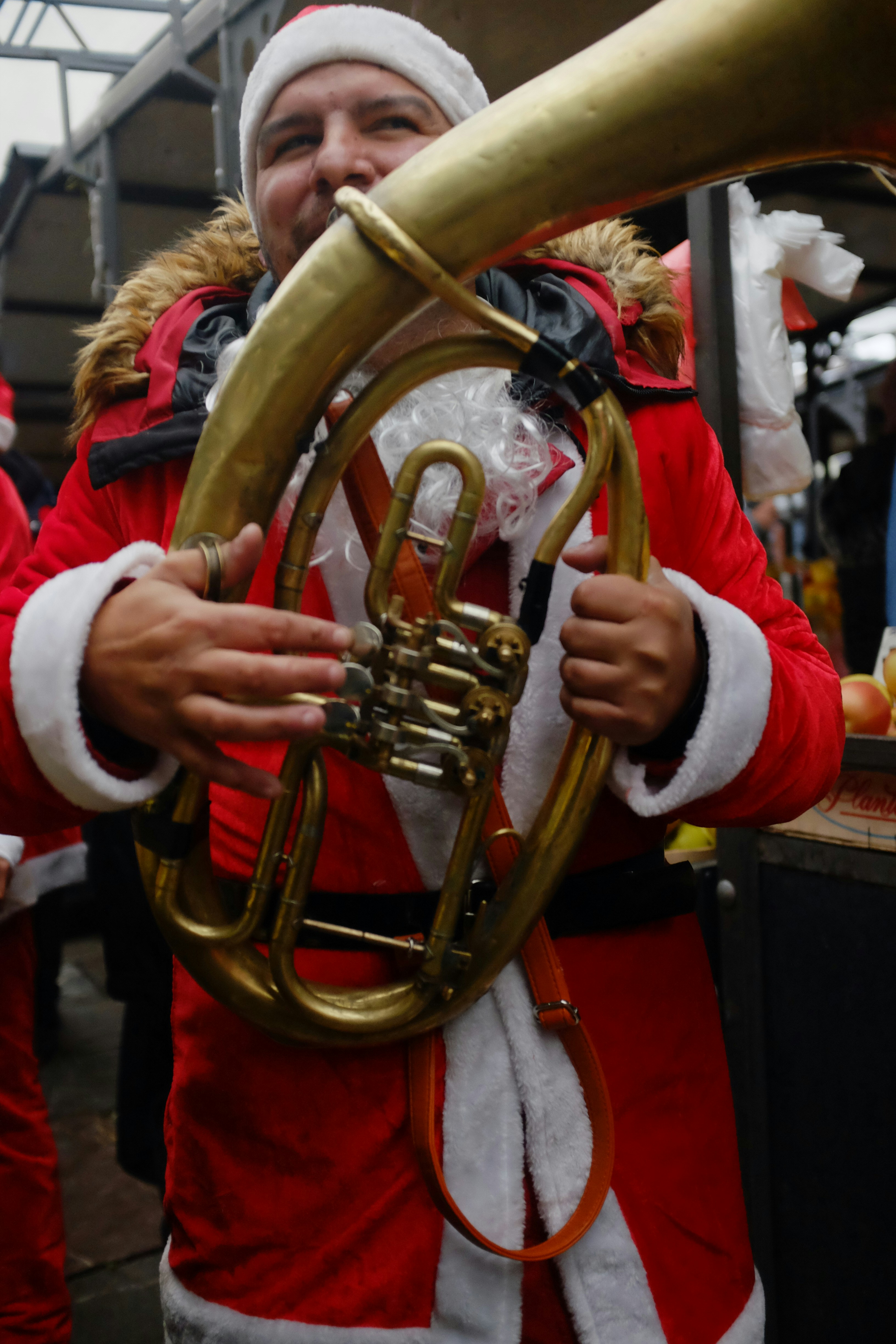 A man in a santa suit is playing a trumpet
