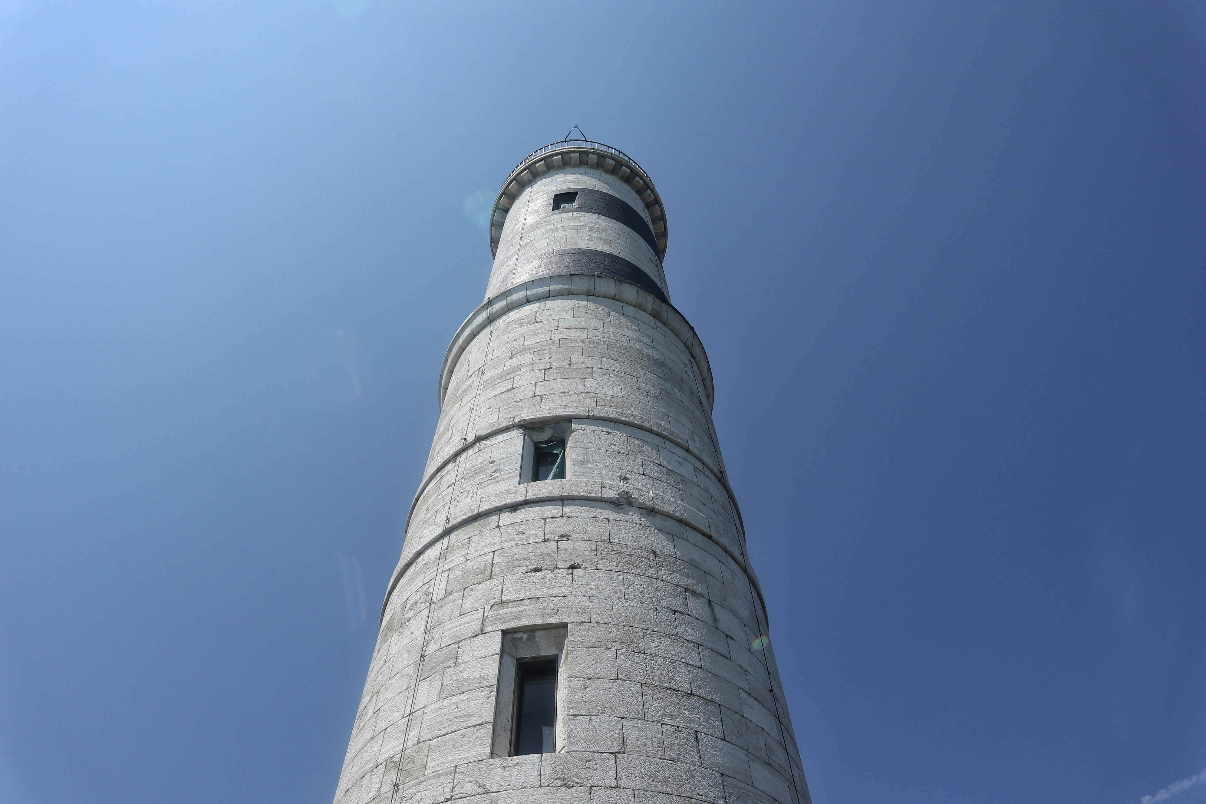A very tall white tower sitting under a blue sky