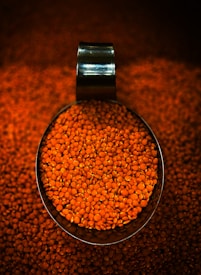 A scoop full of red lentils on a table