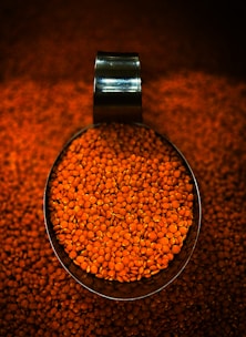 A scoop full of red lentils on a table
