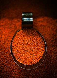 A scoop full of red lentils on a table