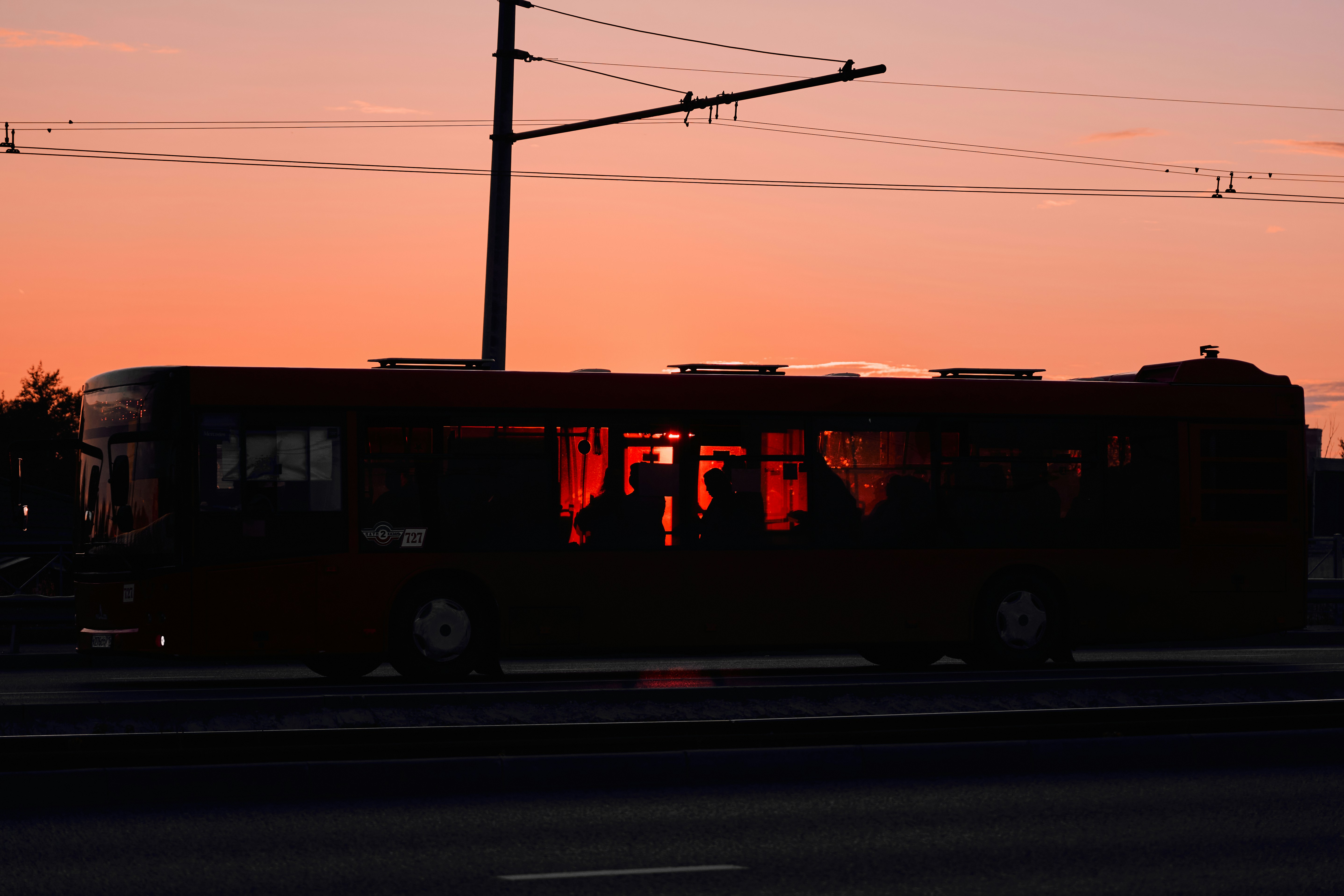 A red bus driving down a street next to a traffic light
