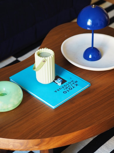 A wooden table topped with a blue book and a donut