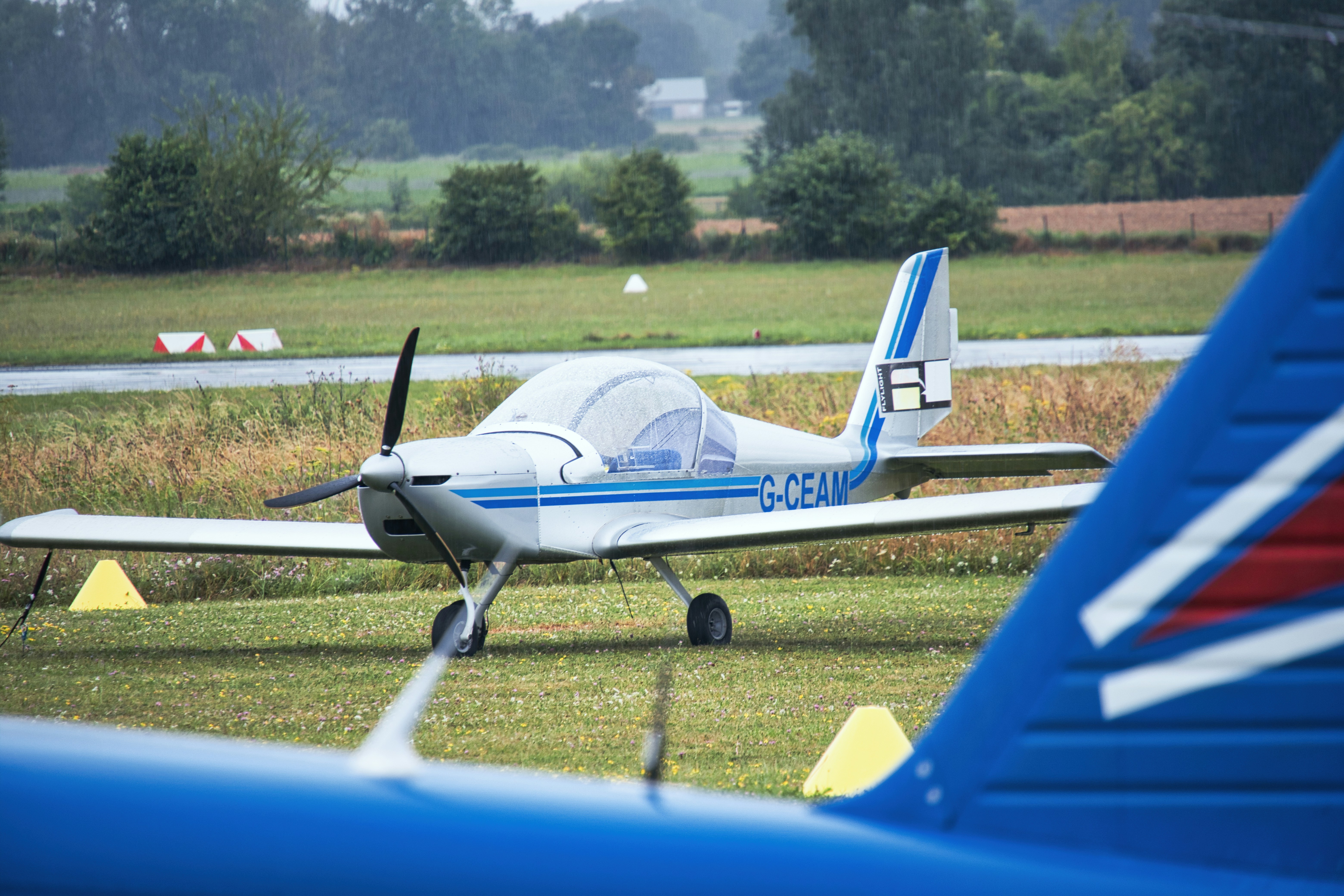 Two small airplanes are parked on the grass